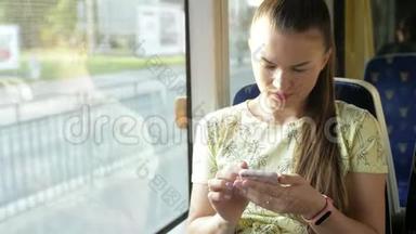 一幅迷人的严肃女孩在<strong>火车上</strong>使用智能手机与朋友聊天的肖像。 慢动作